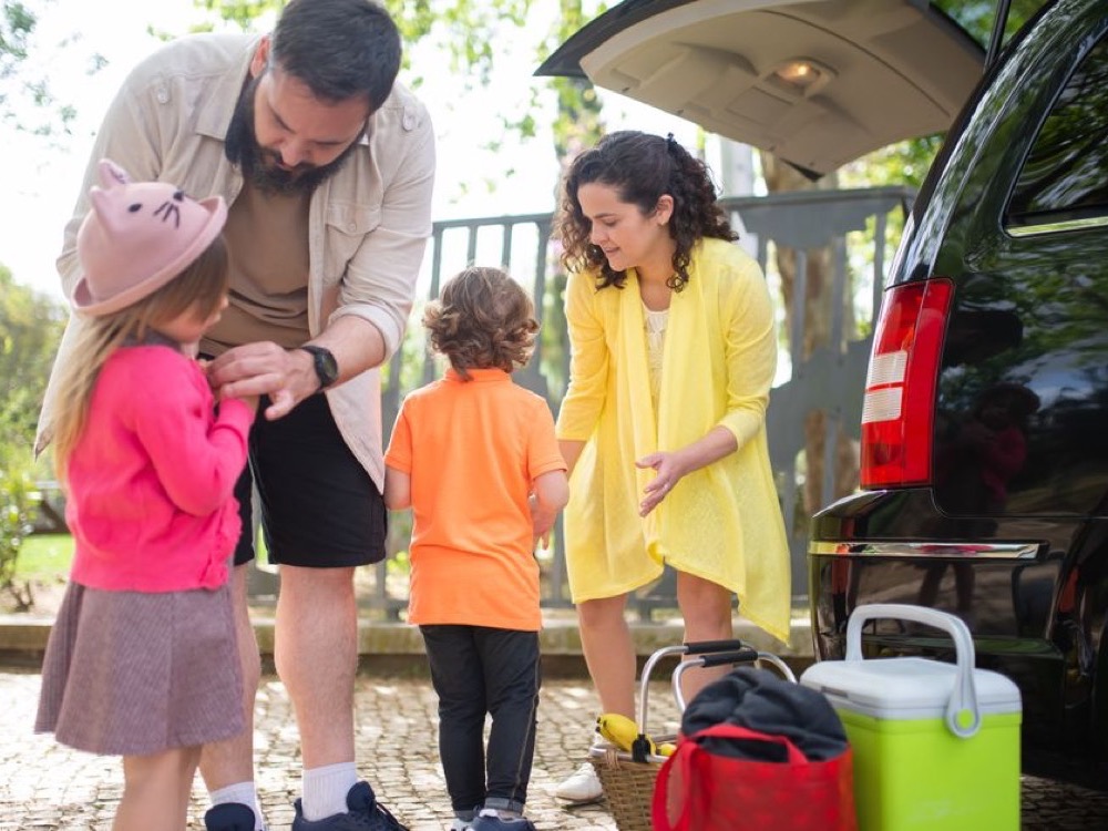 Imagem de família arrumando as malas em um carro para viajar.